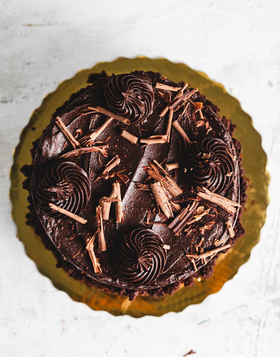 top down view of chocolate fudge cake with rich chocolate frosting rolled in chocolate crumbs with chocolate shaving garnish