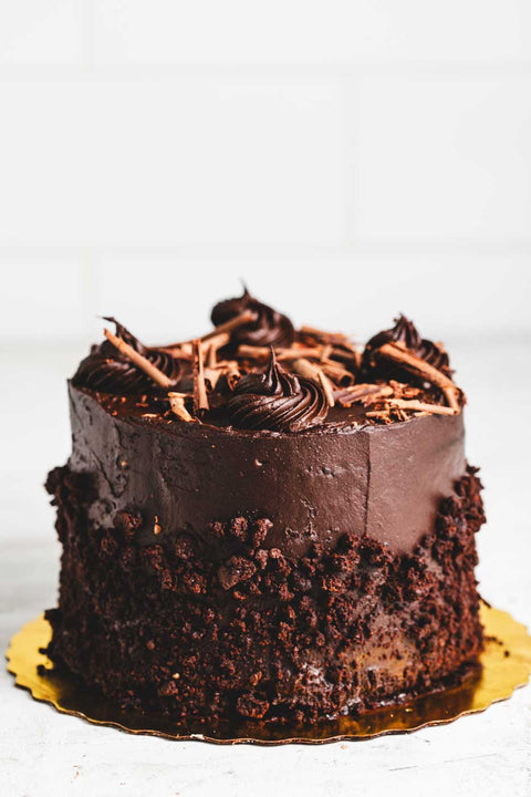 chocolate fudge cake with rich chocolate frosting rolled in chocolate crumbs with chocolate shaving garnish
