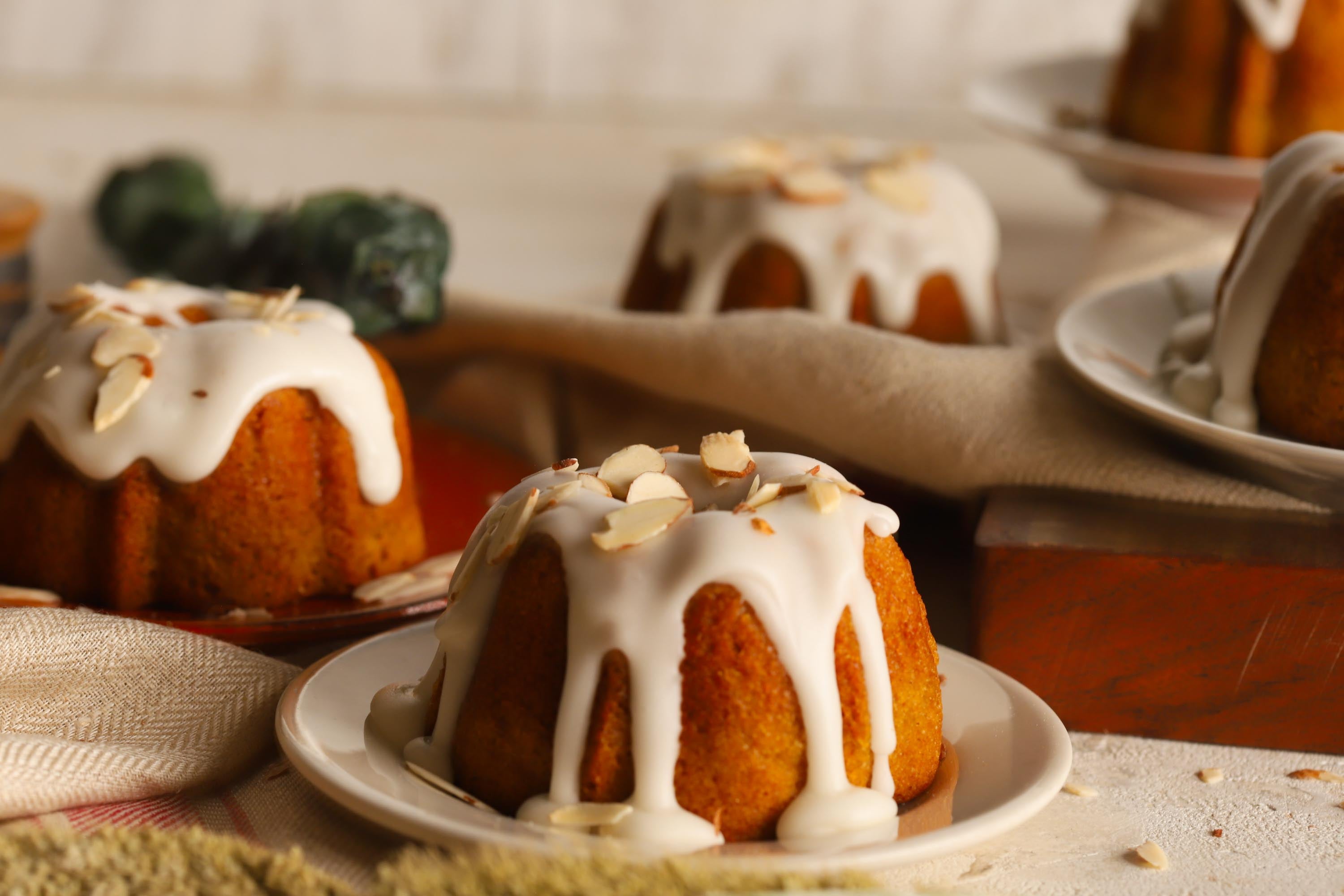 Lemon almond bundt cakes with icing and almonds on top on a rustic background