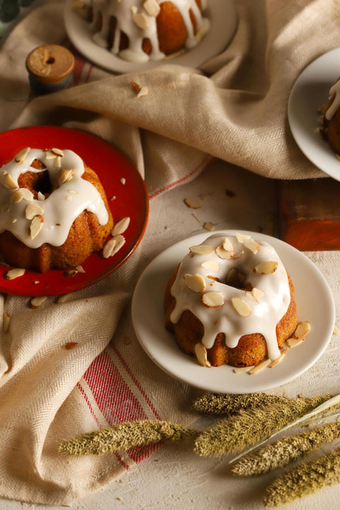 Lemon almond bundt cakes with icing and almonds on top on a rustic background