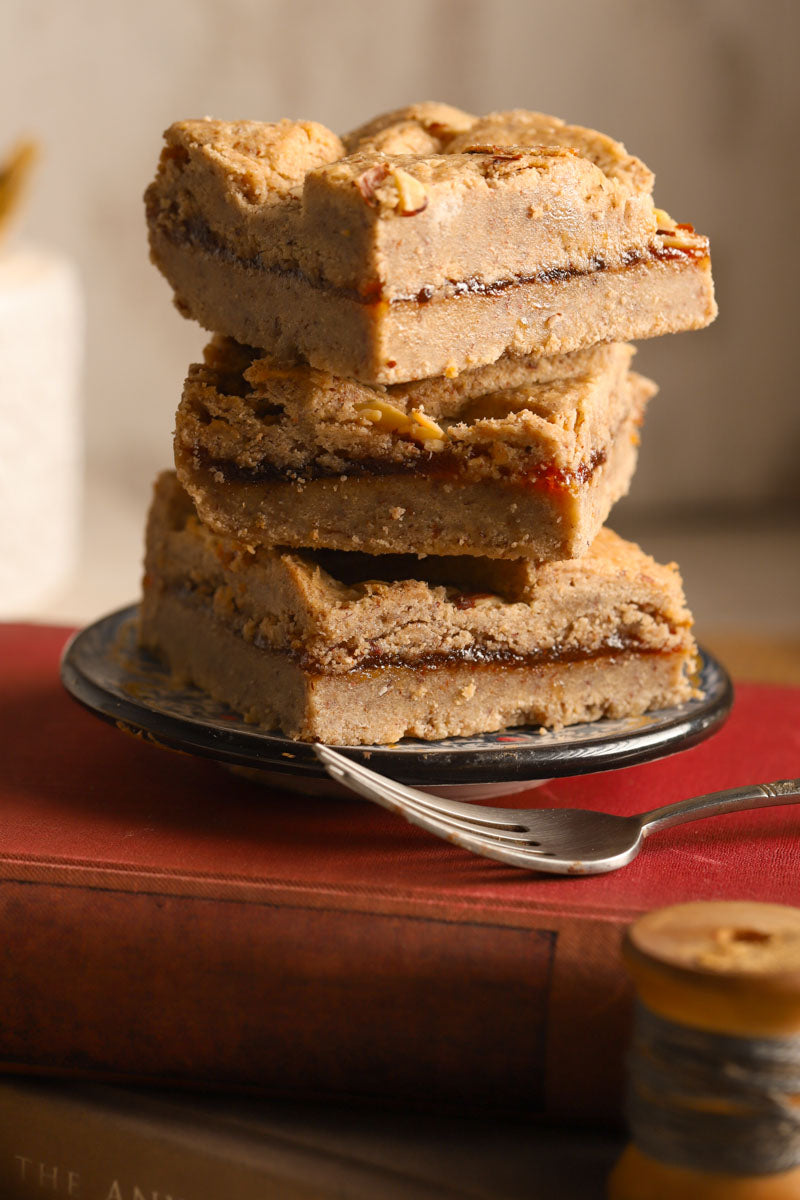 Stack of raspberry hazelnut bars on a plate with a fork on top of a stack of books