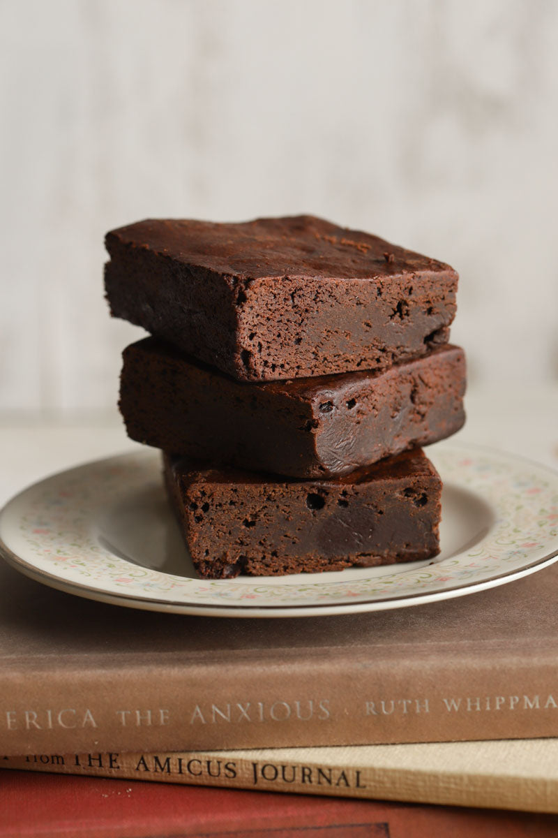 Stack of chocolate chunk brownies on a plate on top of a stack of books