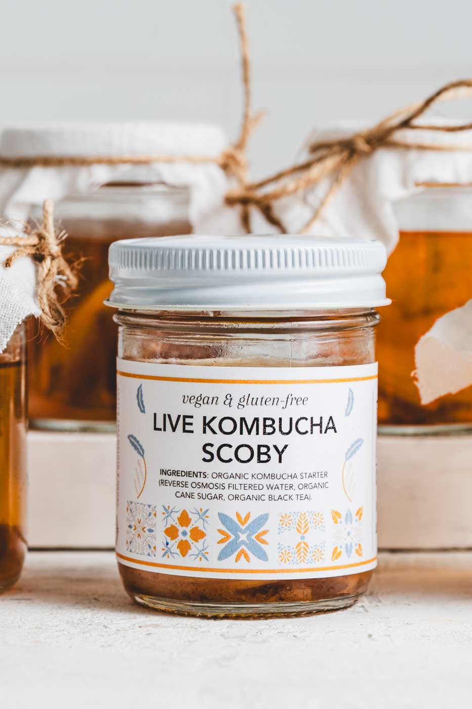 Jar labled live kombucha scoby with more clear glass jars of kombucha scobies in the background