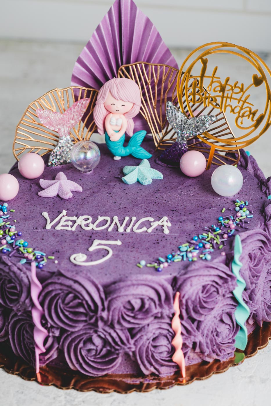 Purple birthday cake with decorative elements and 'Happy Birthday' topper