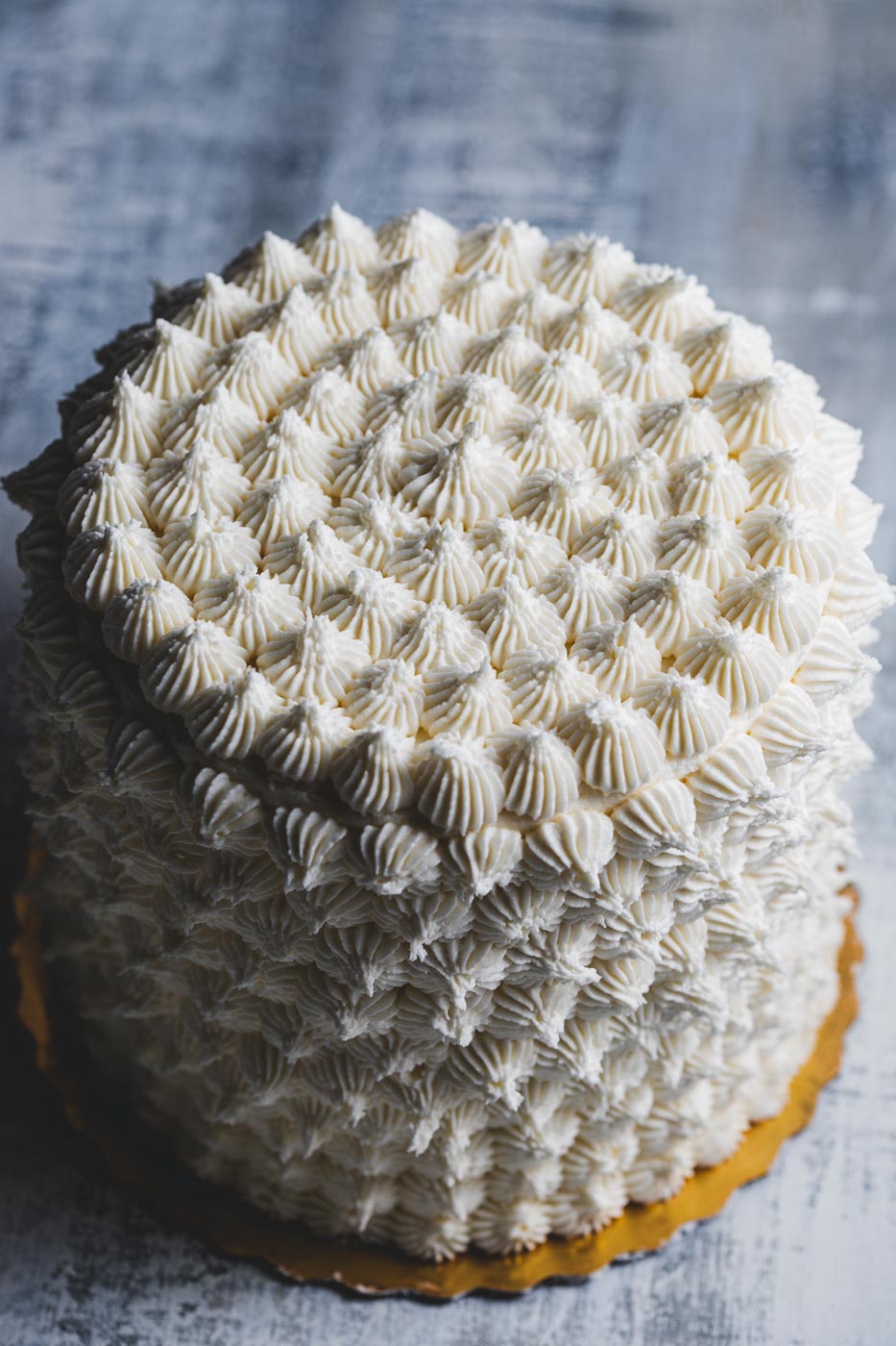 A layer cake with intricate decorative white frosting on a light background