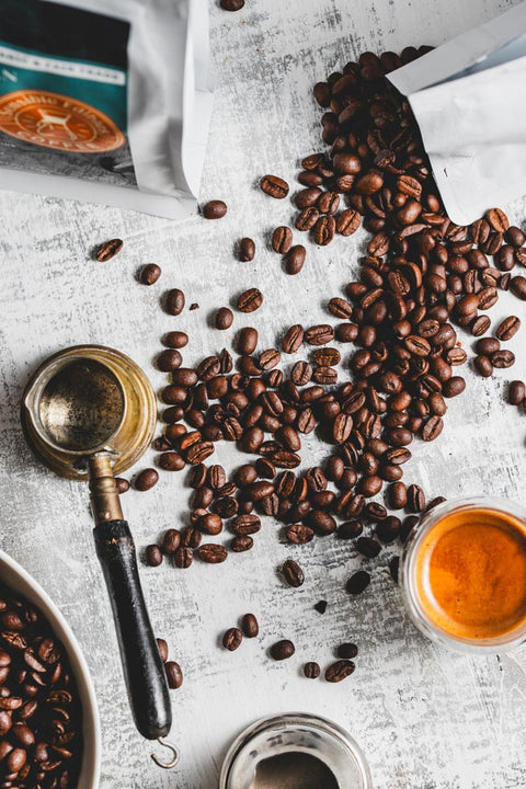 scattered coffee beans on a white background with a cup of coffee and bags of coffee beans