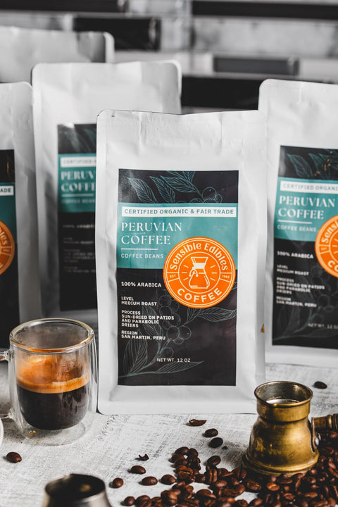 Bags of medium roast peruvian coffee beans with a cup of coffee and scattered coffee beans