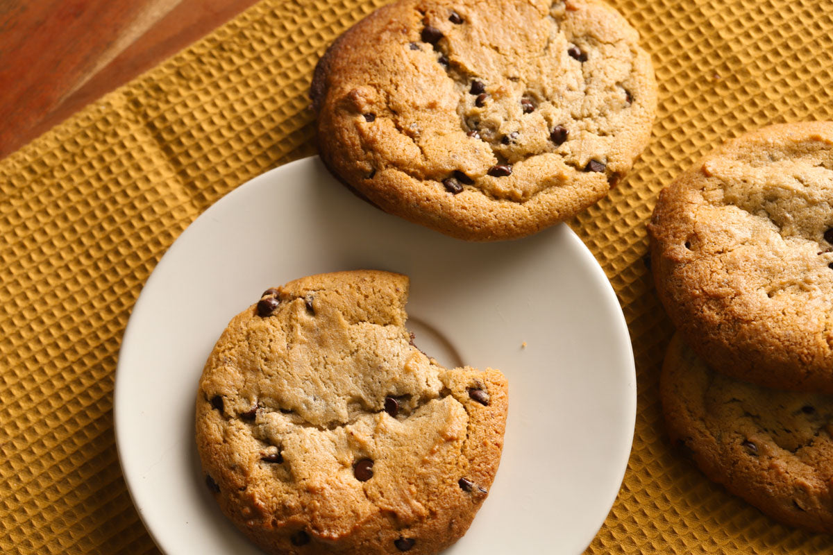 Chocolate chip cookies on a white plate with a yellow textured mat underneath