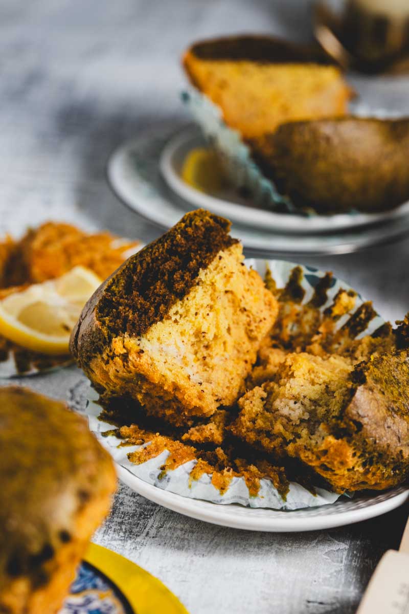 Lemon matcha muffins on and around several plates with lemon slices