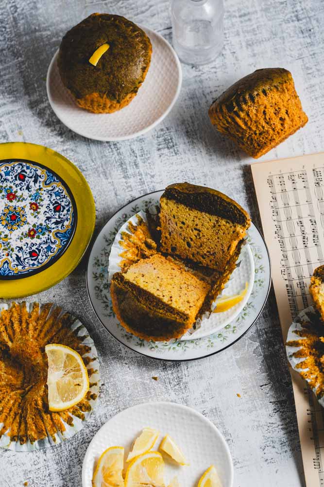 Lemon matcha muffins on and around several plates with lemon slices