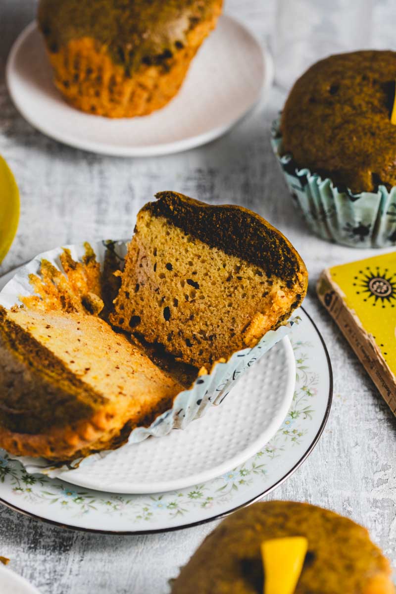 Lemon matcha muffins on and around several plates with lemon slices