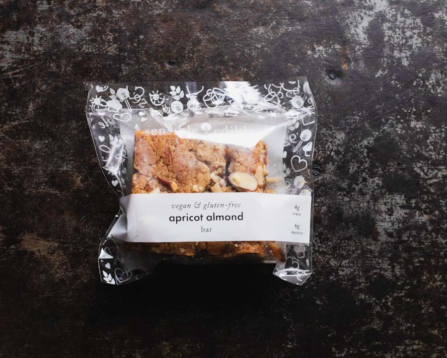 Packaged apricot almond bar on a textured black background.