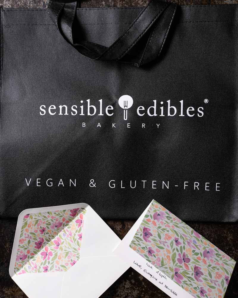 Black Sensible Edibles tote bag with floral greeting cards.