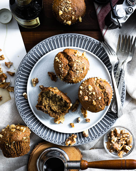 Top view of vegan and gluten-free banana walnut muffins on a decorative plate surrounded by scattered walnuts.